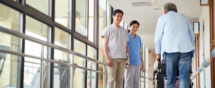 Adult children watching elderly parent using a walker