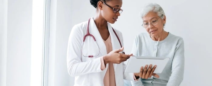 Doctor showing elderly patient information Doctor showing elderly patient information